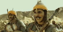a man with a mustache is holding a sword and wearing a helmet