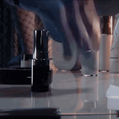 a bottle of lipstick sits on a glass table