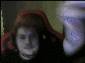 a blurry picture of a man in a red chair with his hand up