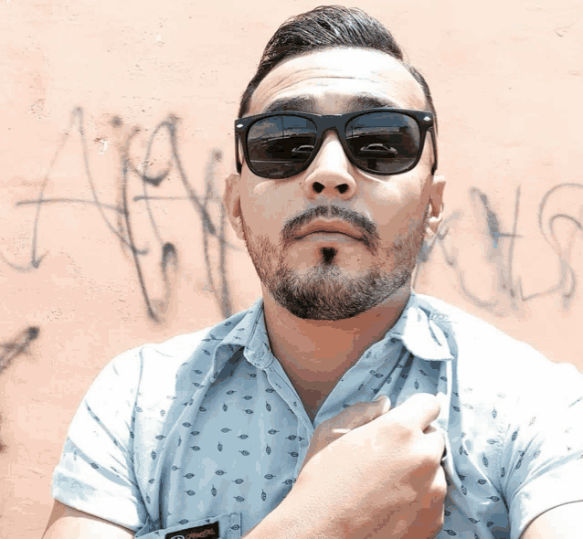 a man wearing sunglasses is standing in front of a wall that has the word always written on it