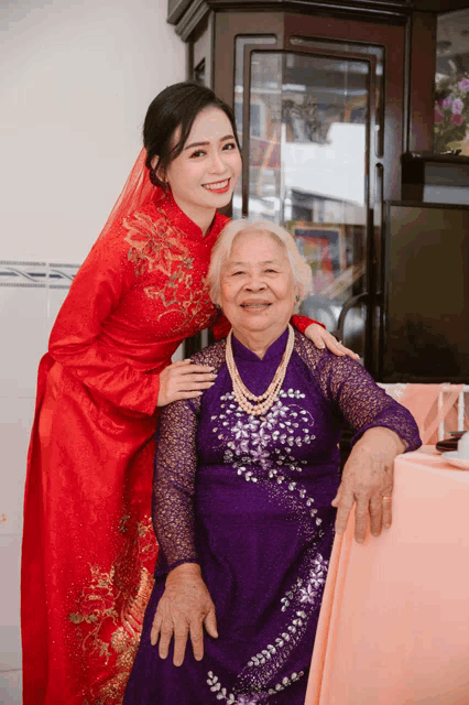 a woman in a red dress is posing for a photo with an older woman in a purple dress