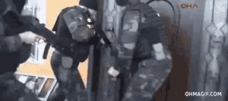 a group of soldiers are standing next to each other in a room holding guns .