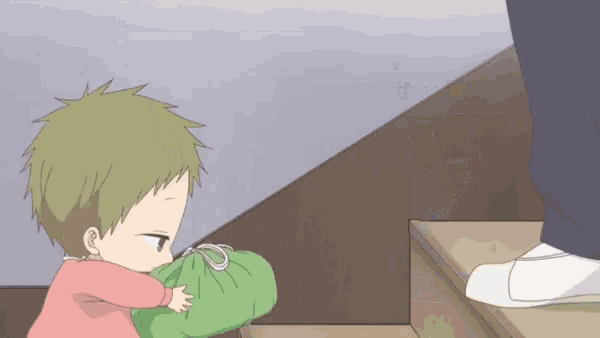a little boy is holding a green bag in his hands while walking down stairs .