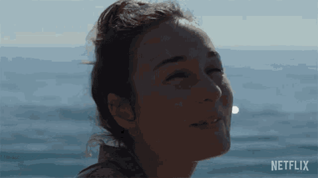 a woman is sitting on a beach with her eyes closed .