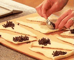 a person is using a spoon to add chocolate chips to a piece of dough