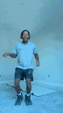 a man wearing headphones is jumping in the air while sitting on a wall .