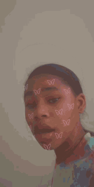 a young girl has pink butterflies painted on her face