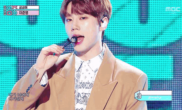 a young man singing into a microphone with the number 3 on the bottom right