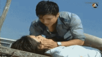 a man kisses a woman on the forehead while she is laying on the ground