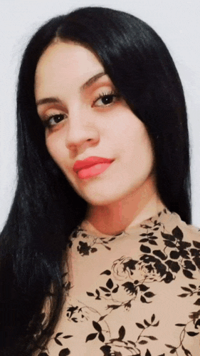 a woman with long black hair wearing a floral shirt