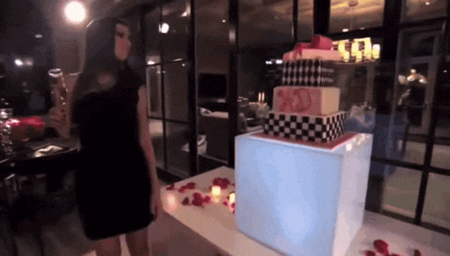 a woman in a black dress stands in front of a cake that says ' sd ' on it