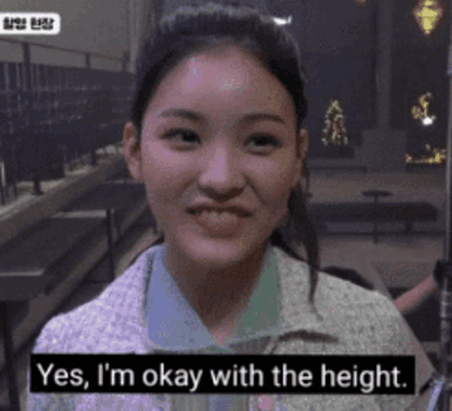 a woman is smiling with the words yes i 'm okay with the height below her