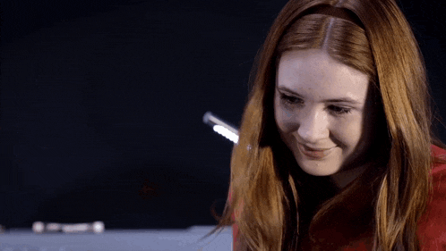 a woman with red hair is smiling and looking down at something