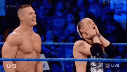 a couple of men are standing in a wrestling ring laughing .
