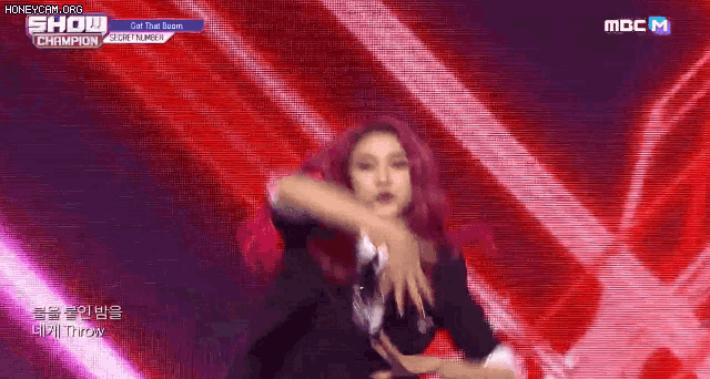 a woman with red hair is dancing on a stage in front of a red background .