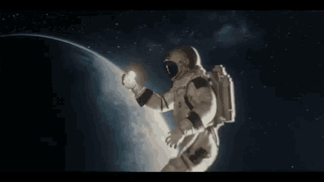 a man in a space suit is standing in front of the earth holding a light .