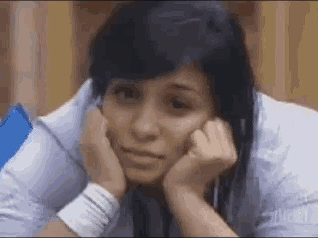 a woman is sitting down with her hands on her face and a sad look on her face .