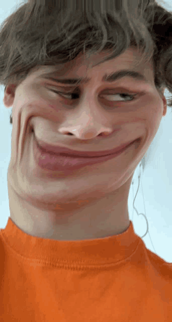 a young man wearing an orange shirt makes a funny face