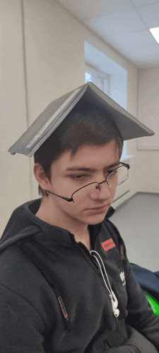 a young man with a book on his head wearing glasses and headphones