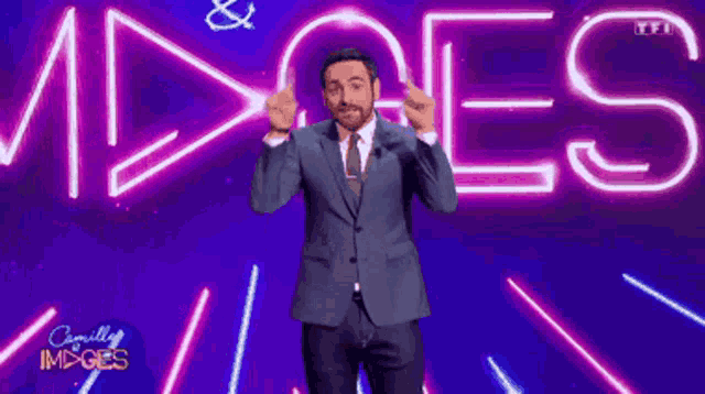 a man in a suit and tie is standing in front of a sign that says camille images
