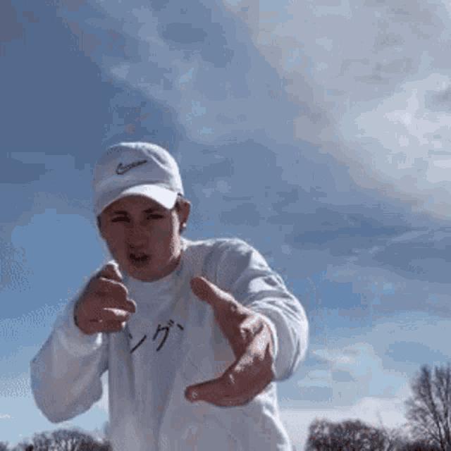 a man wearing a white nike hat and a white sweater is reaching out his hands
