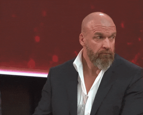 a bald man with a beard is wearing a black suit