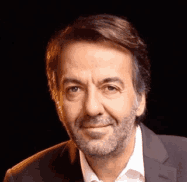 a man in a suit and white shirt is smiling for the camera