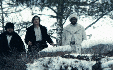 a group of people standing in the snow with one wearing a white hat