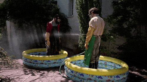 a man wearing a gas mask is spraying another man in a pool