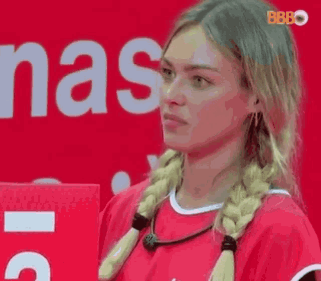 a woman with braids is standing in front of a red sign that says nas .
