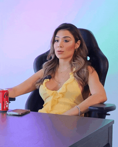 a woman in a yellow dress sits at a desk with a can of coca cola in front of her