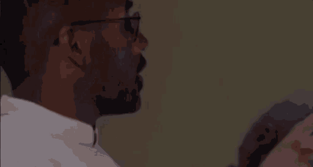 a man wearing glasses and a white shirt is talking to another person