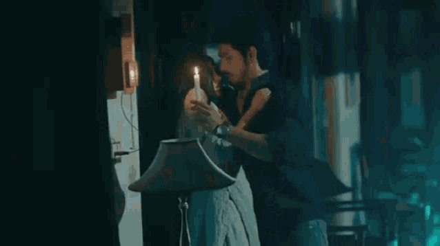 a man and a woman are standing next to each other holding candles .
