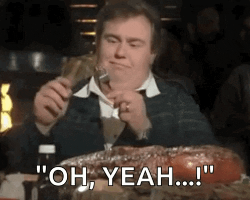 a man is sitting at a table eating a large piece of meat and saying `` oh yeah ... '' .
