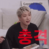a man in a black shirt is sitting on a couch holding a book with chinese writing on it