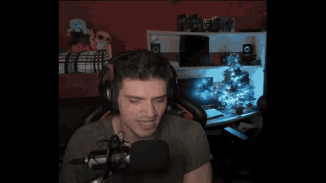 a man wearing headphones is screaming into a microphone in front of a computer monitor