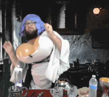 a man wearing a purple wig and glasses is standing in front of a table with a bottle of water on it