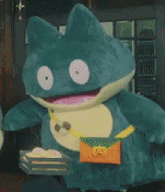 a stuffed animal is holding an orange envelope and a stack of cupcakes .
