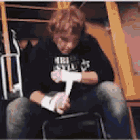 a man is sitting on a chair wrapping his hands with bandages