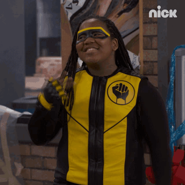 a person in a yellow and black superhero costume with a fist on the chest