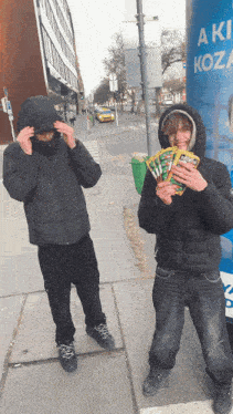 a man holding a bunch of cards next to another man holding a bunch of cards