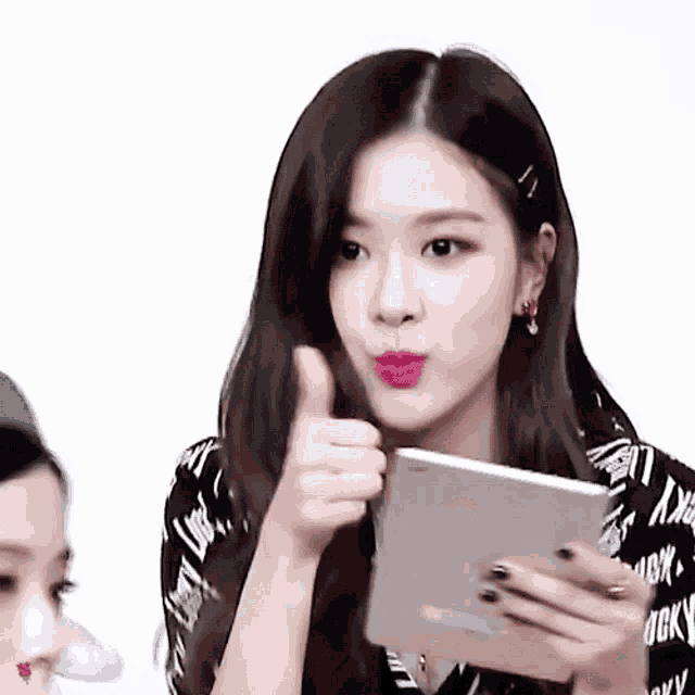 a woman is holding a tablet and giving a thumbs up