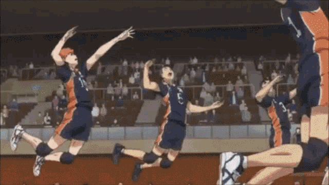 a group of volleyball players are jumping in the air in a stadium .