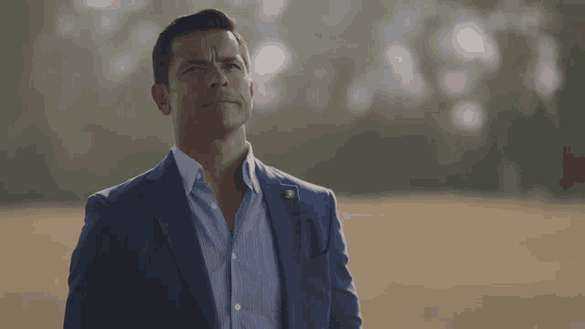 a man in a suit stands in a field looking up