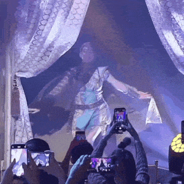 a group of people are taking pictures of a performer on their phones