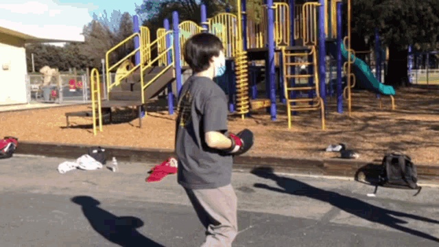 a person wearing a mask standing in front of a playground