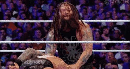 a man with long dreadlocks is wrestling another man in a ring .