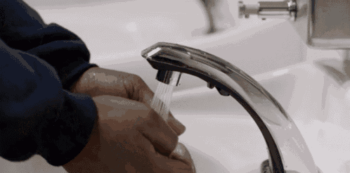 a person is washing their hands under a faucet in a bathroom
