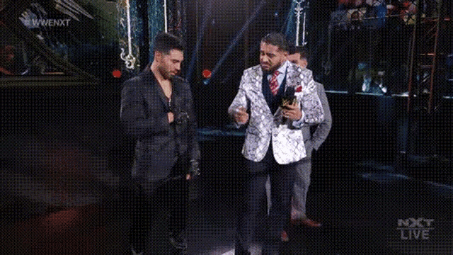 a group of men are standing on a stage holding microphones and one of them is crying .