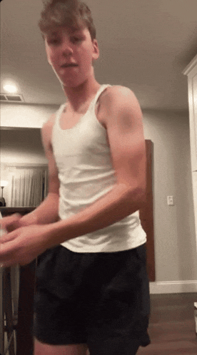 a young man wearing a white tank top and black shorts
